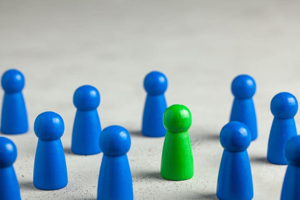 Groep blauwe pionnen met één groene pion als symbool voor de juiste kandidaat