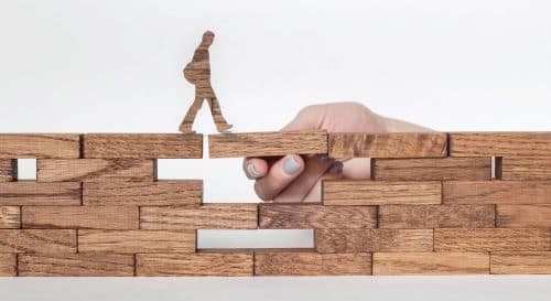 Poppetje loopt over muur en krijgt ondersteuning bij zetten van volgende stap